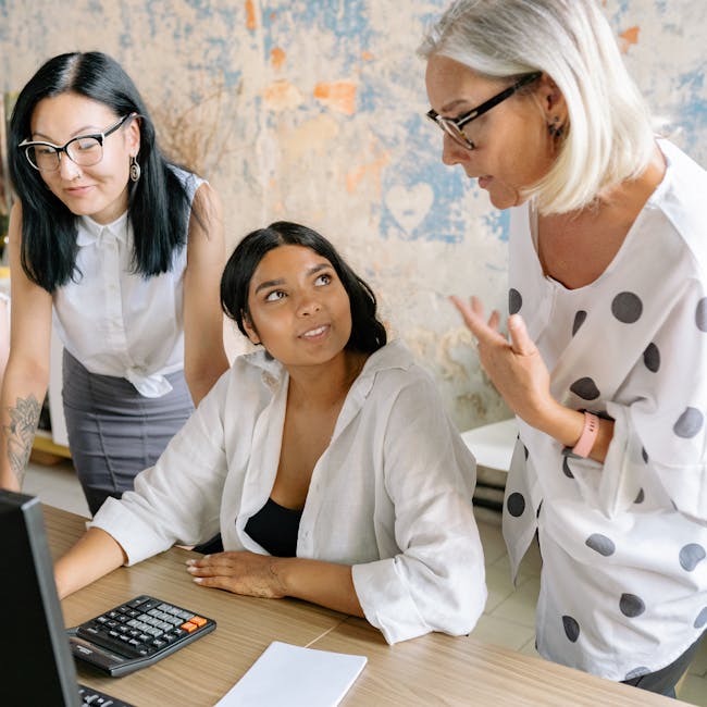 Three colleagues discussing a project in a stylish office setting, emphasizing teamwork and diversity.